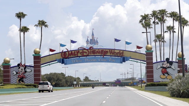Cars drive under a sign greeting visitors near the entrance to Walt Disney World, in Lake Buena Vista, Florida.