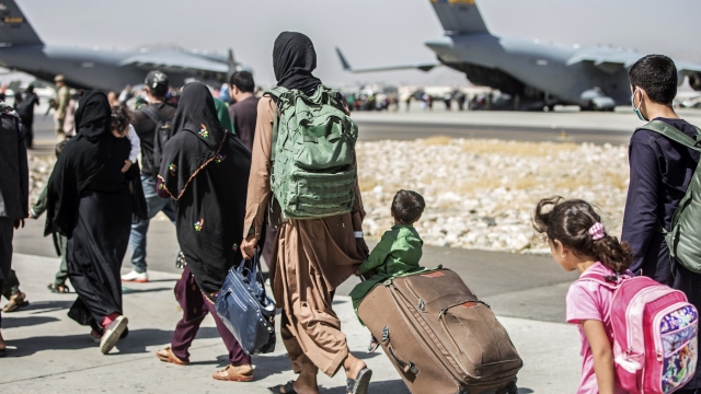 Families walk toward their evacuation flight at Hamid Karzai International Airport in Afghanistan
