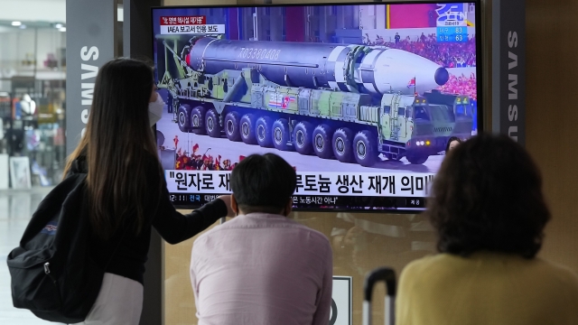People watch a TV screen showing a file image of a North Korean missile in a military parade during a news program.