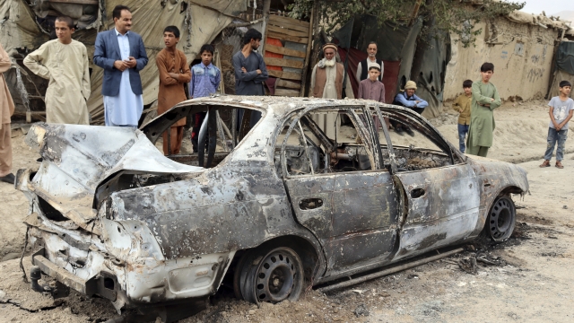 Locals view a vehicle damaged by a rocket attack in Kabul, Afghanistan, Monday, Aug. 30, 2021.