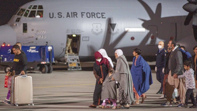 Families evacuated from Kabul, Afghanistan, walk past an U.S air force airplane that flew them to Kosovo.