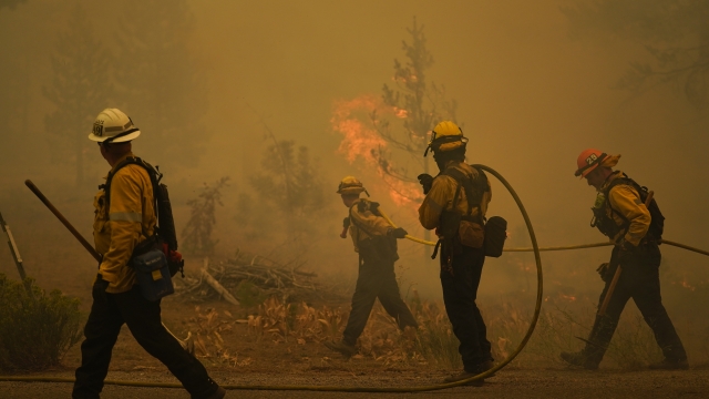 Firefighters carry water hoses while battling the Caldor Fire near South Lake Tahoe, Calif., Tuesday, Aug. 31, 2021.