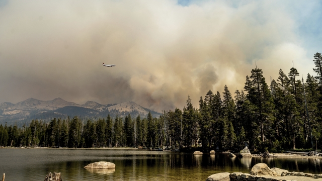 A tanker flies over Wrights Lake while battling the Caldor Fire in Eldorado National Forest, Calif.
