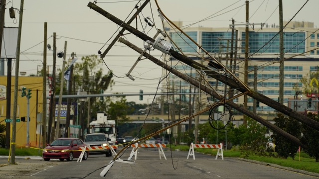 Vehicles are diverted around utility poles damaged by the effects of Hurricane Ida.