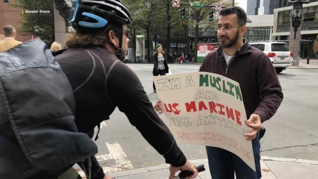 Man shows cyclists a sign.