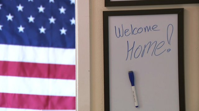 Welcome sign hangs in front of a flag.
