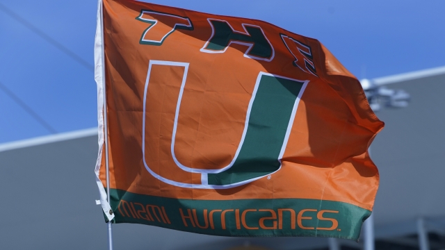 Miami flags fly in the parking lot before an NCAA college football game.