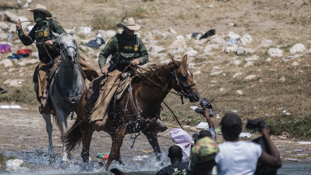 U.S. Border Patrol officers on horseback confront migrants