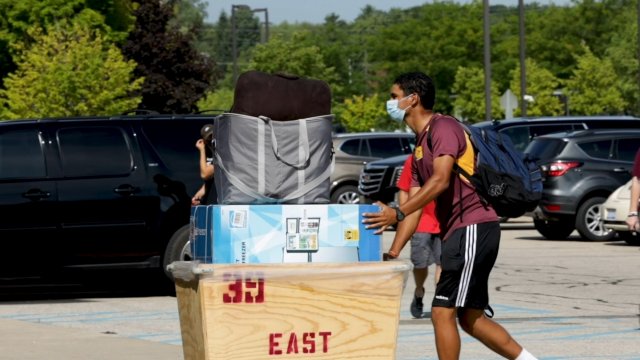 Student pushes belongings in a parking lot.