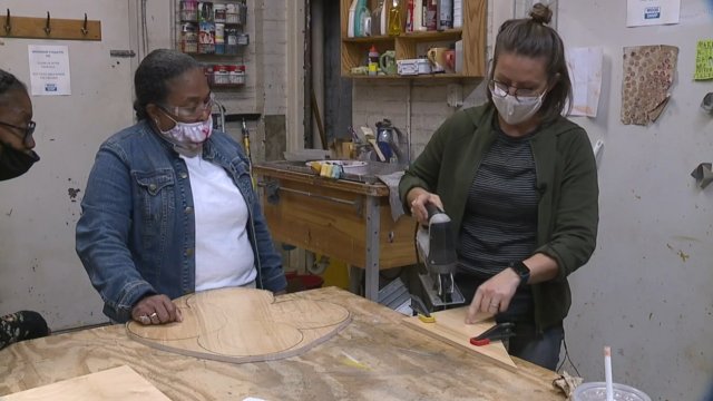 Women cut pieces of wood.
