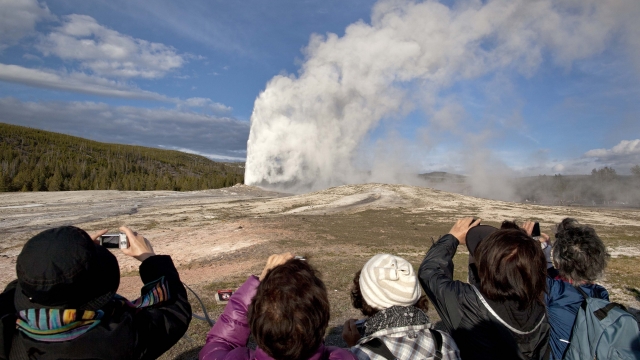 Tourists photograph Old Faithful geyser in Yellowstone National Park, Wyoming.