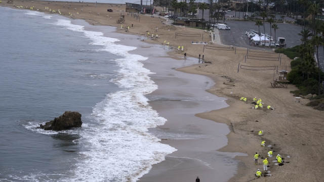 Workers in protective suits clean the contaminated beach in Corona Del Mar after an oil spill in Newport Beach, Calif.