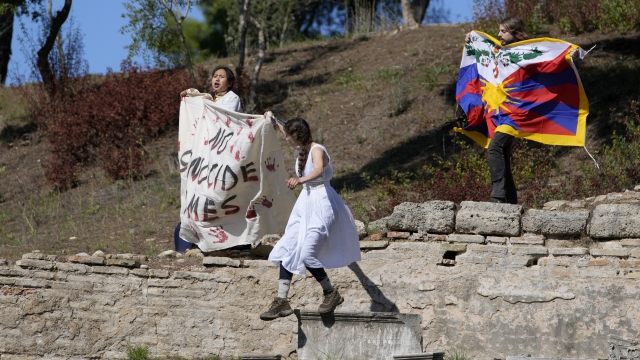 Protesters displaying a Tibetan flag and a banner reading "No genocide games"