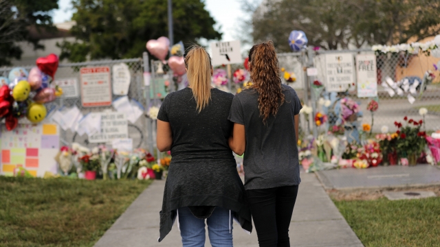 Two people stand in front of a makeshift memorial.