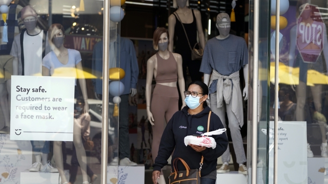 A woman walking out of a store with a mask on.