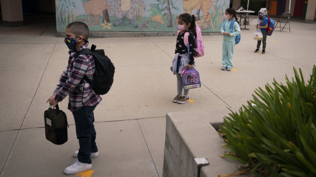 Socially distanced kindergarten students wait for their parents to pick them up.