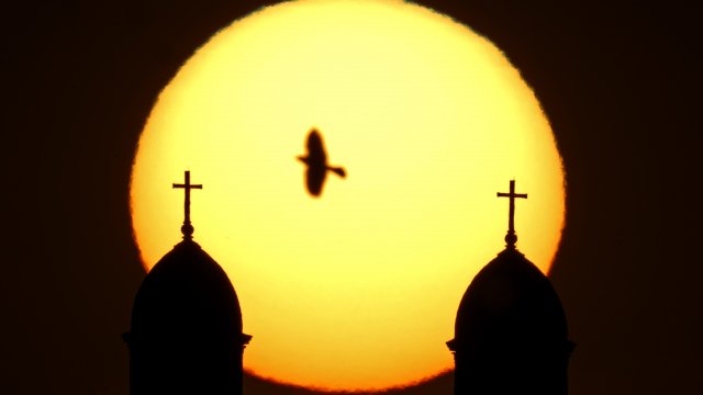 Silhouettes of two church steeples are seen against the rising sun