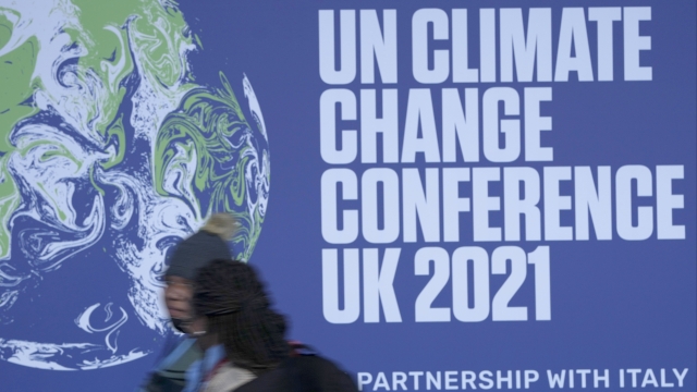 Attendees walk past a banner at the venue of the COP climate conference.
