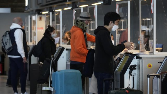 Travelers show their documents at an airport check-in desk.