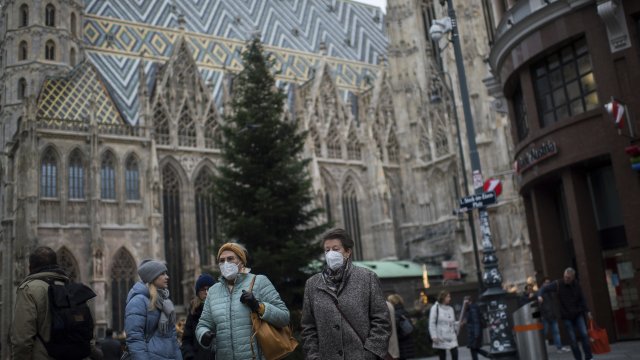 People wearing face masks walk in front of St. Stephen's Cathedral in Vienna, Austria
