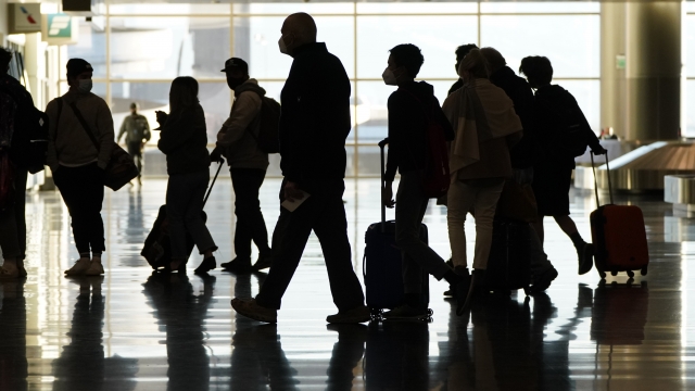 Travelers wait in line to go through a security checkpoint screening at an airport.