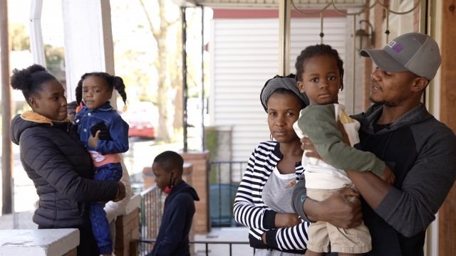 A Haitian refugee family stands on a porch.