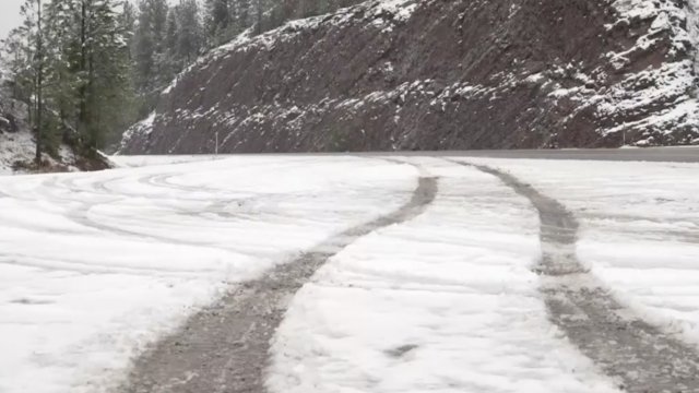 Tire marks run down a snowy road.