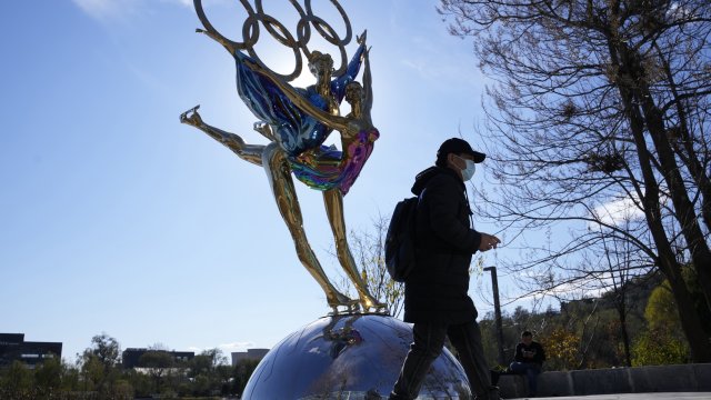 A visitor to the Shougang Park walks past the a sculpture for the Beijing Winter Olympics