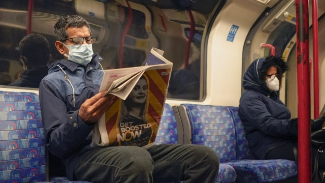 A man wears a face mask as he reads a newspaper on a London Underground train, in London, Thursday, Dec. 16, 2021.