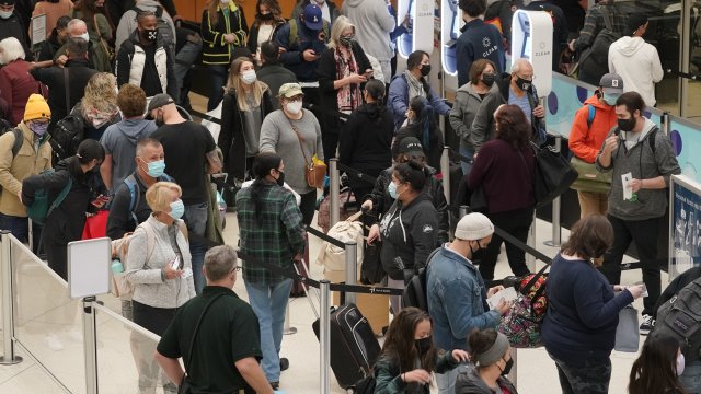 Travelers wear masks as they wait in a line for a TSA security check.