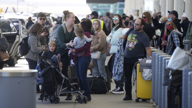 Travelers queue up at the Southwest Airlines curbside check-in area at Denver International Airport Sunday, Dec. 26, 2021.