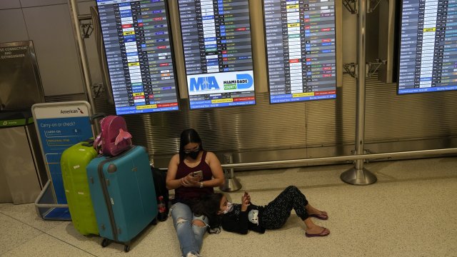 Travelers lay underneath a screen at the airport.