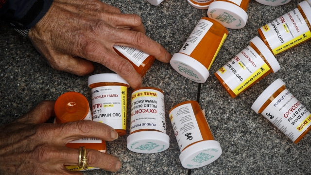A protester gathers containers that look like OxyContin bottles at an anti-opioid demonstration