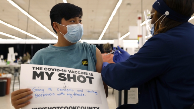 A boy holds a sign in support of COVID-19 vaccinations as he receives his first Pfizer vaccination