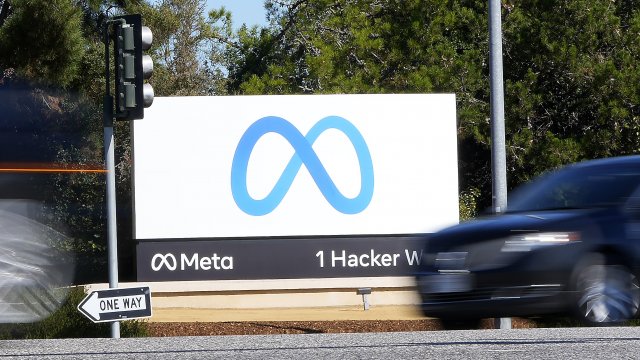 Cars drive past Facebook's new Meta sign at the company's headquarters.