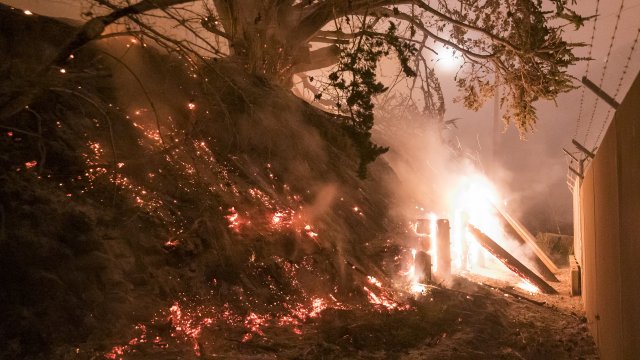 A wildfire burns a fence near Highway 1.