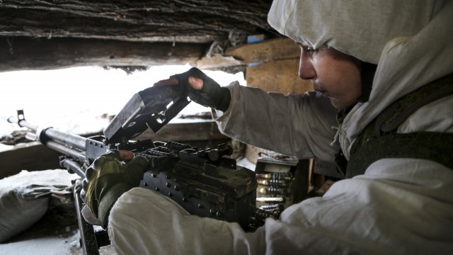 A serviceman checks his machine gun.