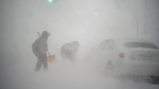 A stranded motorist gets help shoveling out their car from a passerby with a shovel in Providence, R.I.