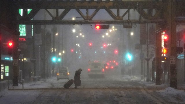 A pedestrian walks across snowy streets.