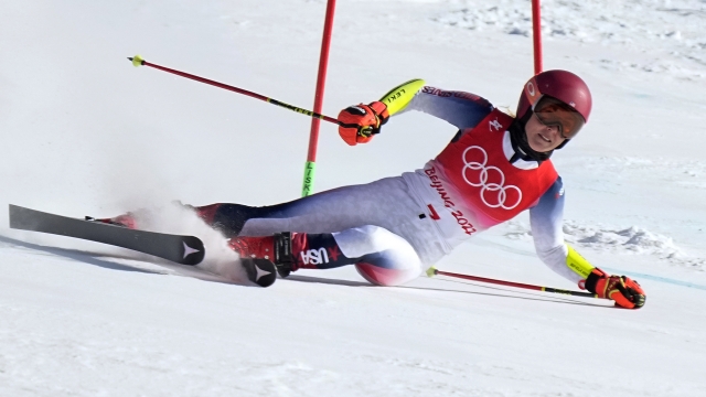 Two-time Olympic gold medalist Mikaela Shiffrin slides across the snow after falling in the giant slalom at the Beijing Games