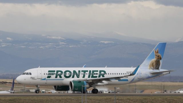 A Frontier Airlines jetliner taxis to a runway to take off.