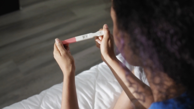 A woman looks at a pregnancy test.
