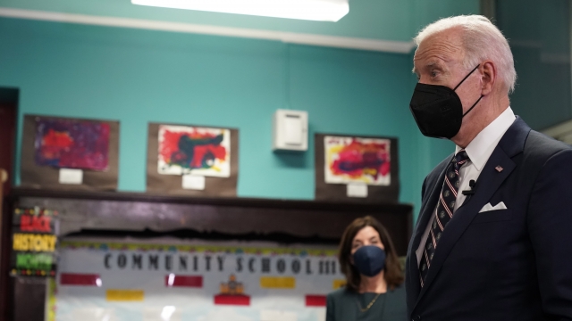 A masked President Joe Biden listens during a school event.