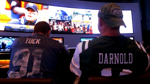 Fans of the New York Giants and Jets watching a football game after placing bets.
