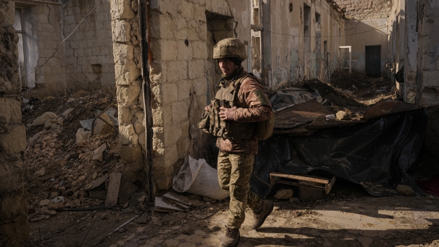 A Ukrainian serviceman walks inside a destroyed house