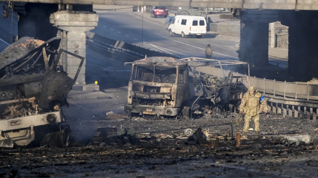 A Ukrainian soldier walks past debris of a burning military truck