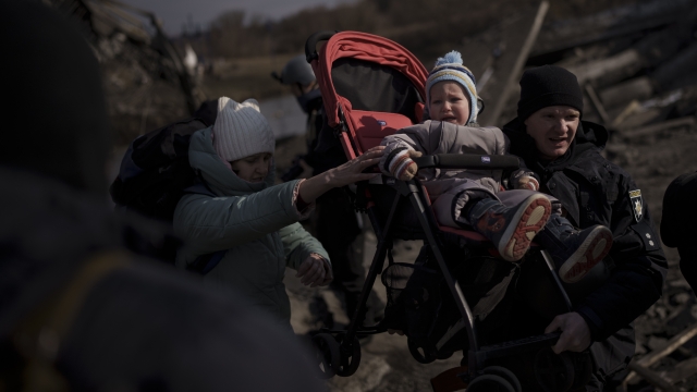 A child is carried on a stroller across an improvised path while fleeing Ukraine