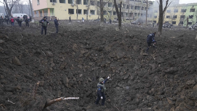 Ukrainian soldiers and emergency employees work at the side of the damaged by shelling maternity hospital in Mariupol