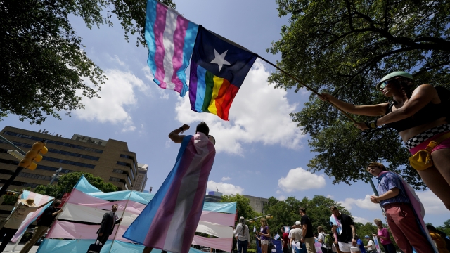 Demonstrators wave a pride flag.