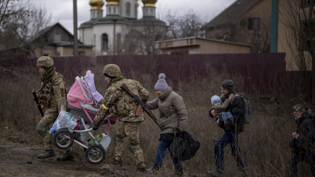 Ukrainian soldiers help a fleeing family crossing the Irpin river on the outskirts of Kyiv, Ukraine.